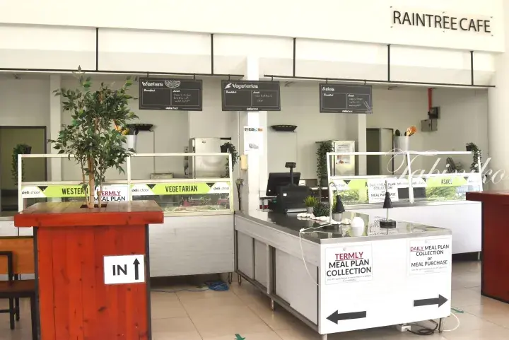 Raintree Cafe food counter with Western, Vegetarian, and Asian meal options and daily meal plan collection signs.