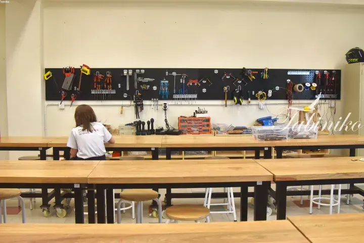 Student working at a well-organized workshop table with tools on a pegboard wall at HEI International School.