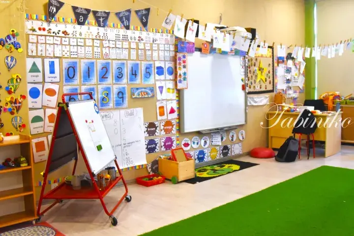 Colorful classroom with math posters, a whiteboard, and children’s artwork displayed on the walls.