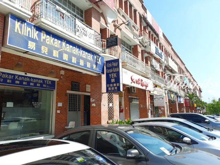 Klinik Pakar Kanak-kanak YEK storefront with blue signage in a brick commercial building with parked cars.