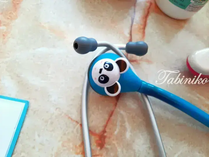 Close-up of a blue children’s toy stethoscope with a panda face design on a marble countertop.