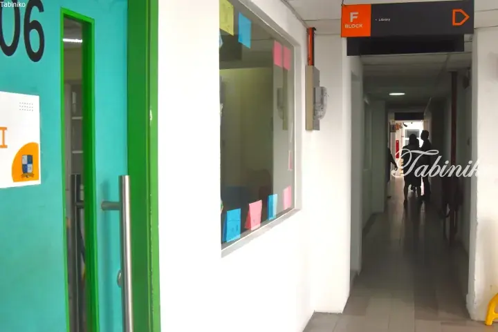 Corridor view of F Block at a Malaysian school, showing a teal classroom door and directional signage for the library.