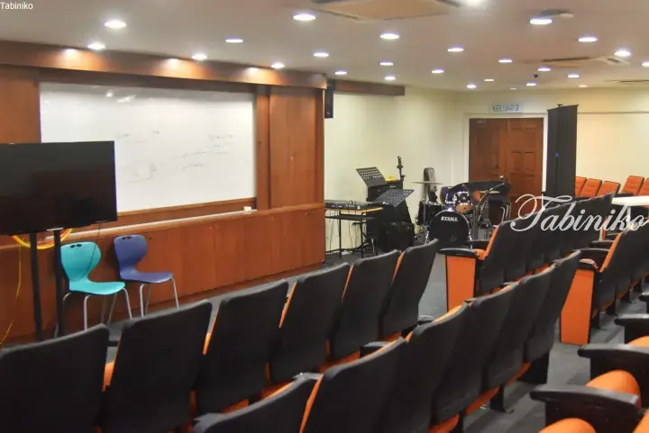 A modern lecture hall with tiered seating, a whiteboard, and musical instruments set up for a class.