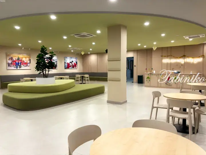 Modern school lobby with curved green seating, wooden tables, and a reception desk.