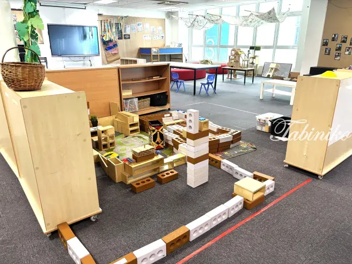 Children&rsquo;s playroom with wooden blocks, low furniture, and a TV screen in a bright, modern space.