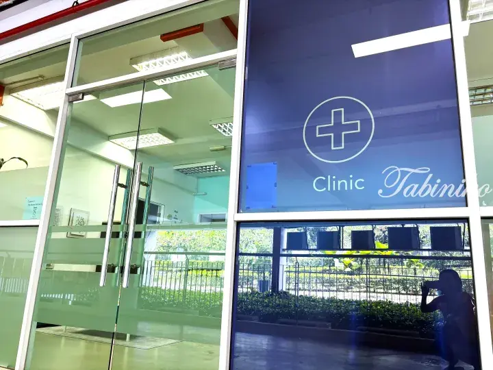Glass entrance door with a blue frosted panel displaying the Clinic Tabiniko logo and medical cross symbol.