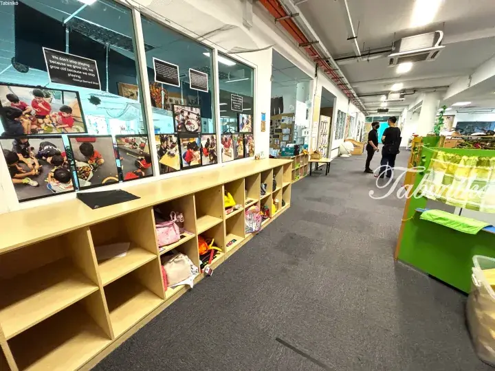 Modern kindergarten hallway with wooden cubbies, children&rsquo;s photos, and inspirational quotes on glass walls.
