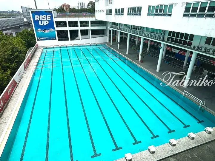 Aerial view of the IGB International School swimming pool with lane markers and a Rise Up banner.