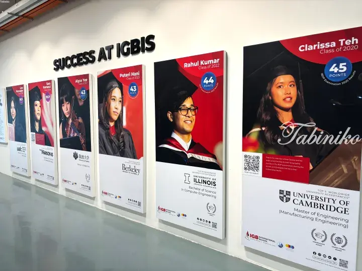 Wall display at IGB International School showcasing student success with posters of graduates and their university acceptances.