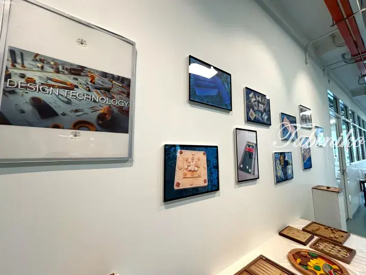Wall display of wooden board games and design technology posters in a modern showroom.