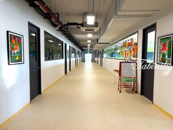 Bright school corridor with colorful children&rsquo;s artwork on walls and a display board listing art media and skills.