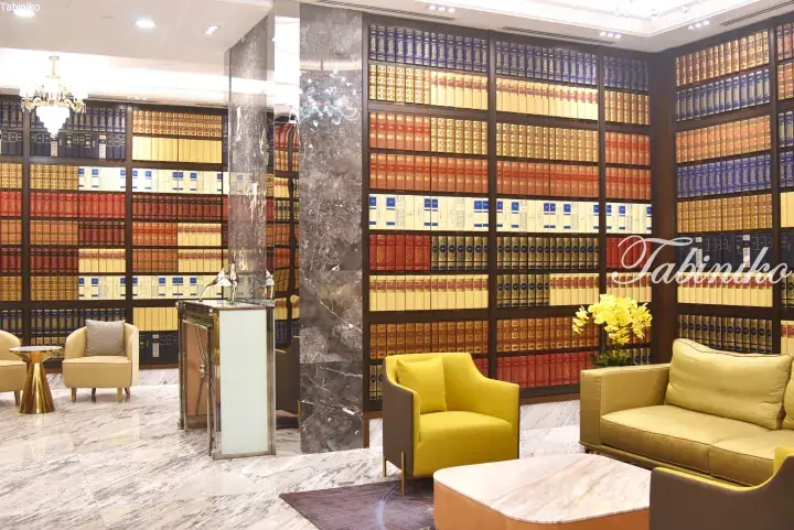 Luxurious library lounge with floor-to-ceiling bookshelves, marble floors, and elegant seating.