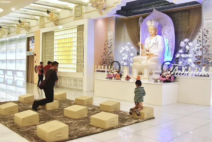 Devotees praying before a white Ksitigarbha Bodhisattva statue at a modern Buddhist temple in Malaysia.