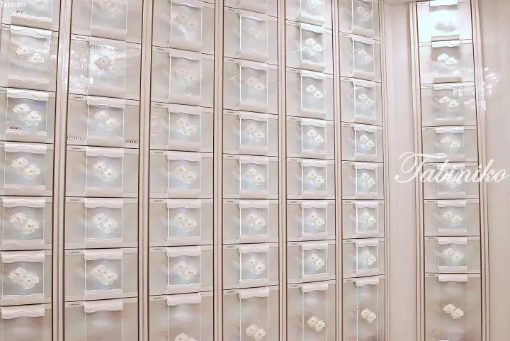 Wall of elegant glass display cases featuring white floral arrangements in a luxury property showroom.