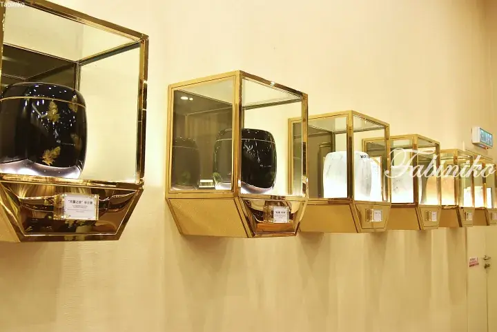 Luxury urns displayed in illuminated gold glass cases at a funeral home in Malaysia.