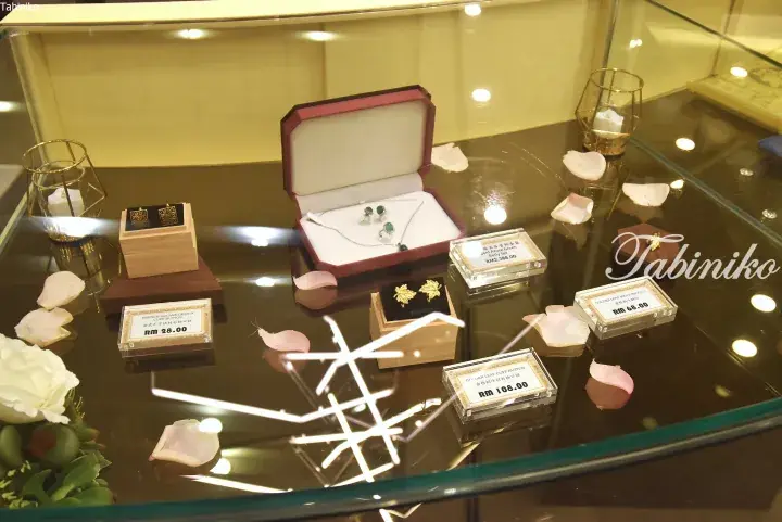 Glass display case featuring jewelry sets and cuff buttons with price tags in Malaysian Ringgit.