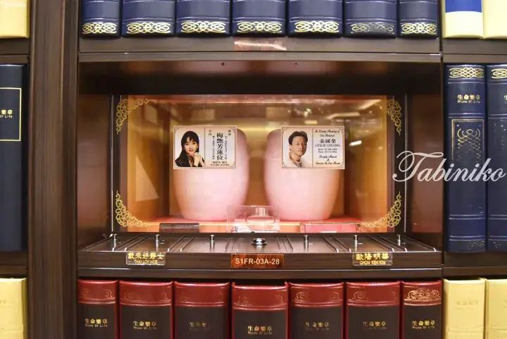 Cremation urns of Anita Mui and Leslie Cheung displayed in a glass niche at a columbarium.