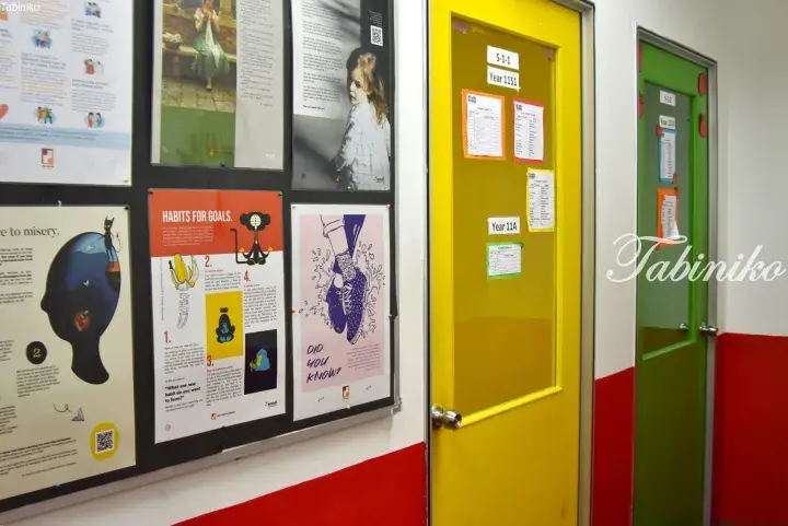 School hallway with posters on habits and goals, and yellow and green classroom doors labeled Year 11A and Year 11S1.