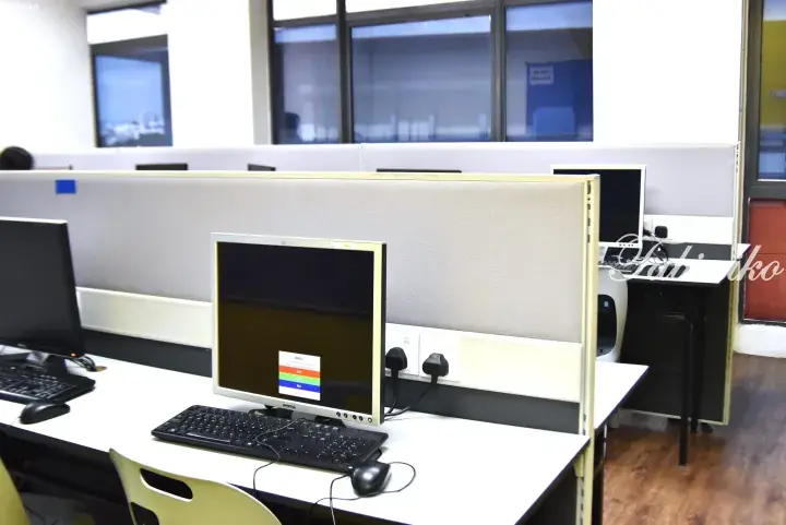 Modern office cubicle with Dell monitor, keyboard, and mouse on white desk in open workspace.