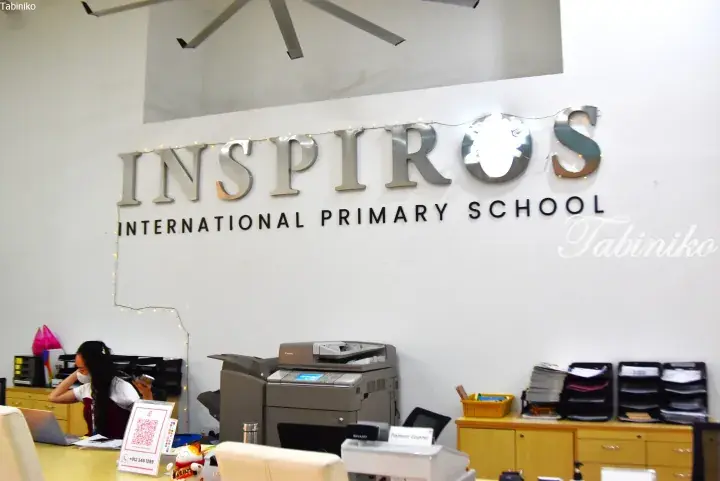 Reception area of Inspiros International Primary School in Malaysia with signage and office equipment.