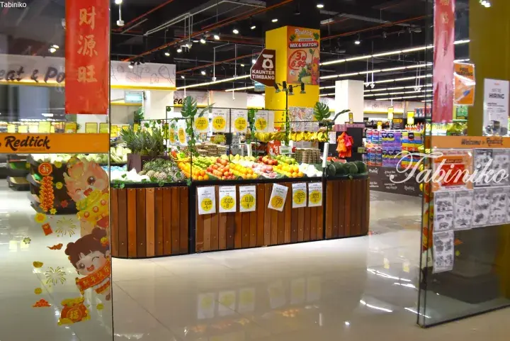 Fresh fruit display at Redtick Supermarket entrance with Chinese New Year decorations and price tags.