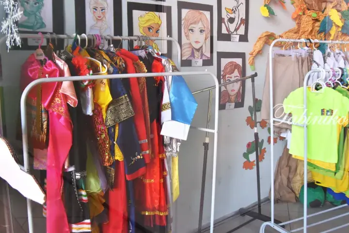 Colorful children&rsquo;s costumes on racks inside a classroom, with Frozen character drawings on the wall.