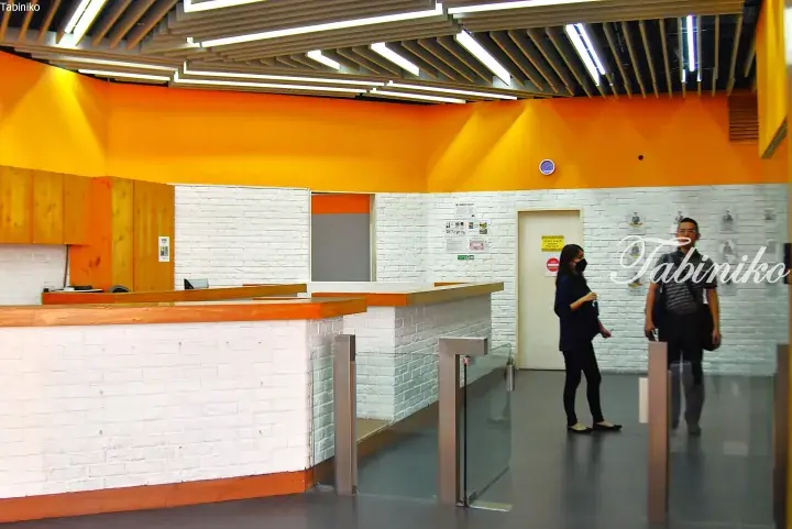 Modern reception area with orange walls, white brick counters, and wooden slat ceiling at a Malaysia property.