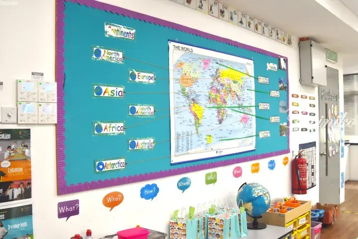 Classroom bulletin board displaying a world map with labeled continents and oceans for educational purposes.