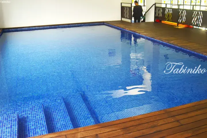 Indoor swimming pool with blue mosaic tiles and wooden deck at a Malaysia property