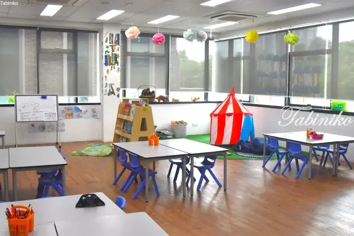 Bright classroom with child-sized tables, blue chairs, a play tent, and colorful decorations in a Malaysia property.