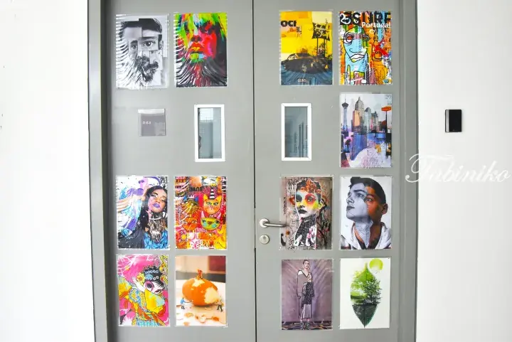 Grey double doors decorated with colorful artistic posters and a &ldquo;D 4.3&rdquo; room number plate.