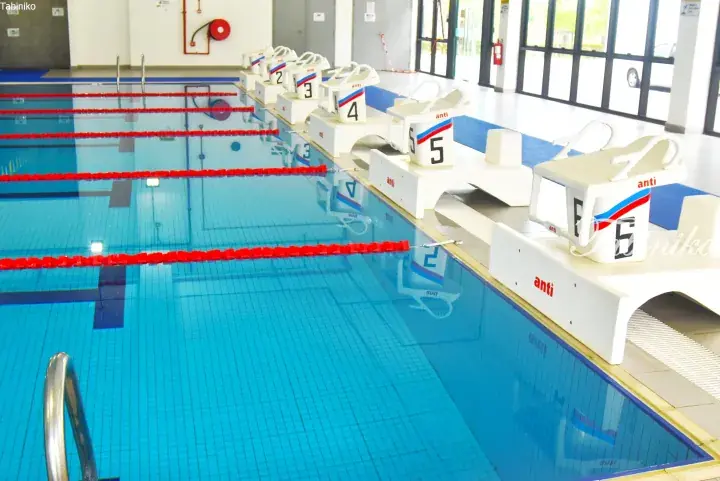 Swimming pool with numbered starting blocks and lane dividers in a modern indoor facility.