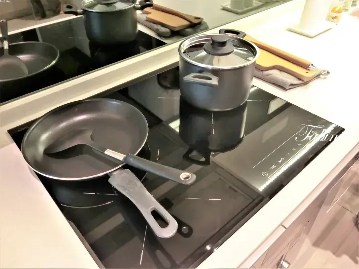 Modern induction cooktop with a frying pan and saucepan in a sleek kitchen setting.
