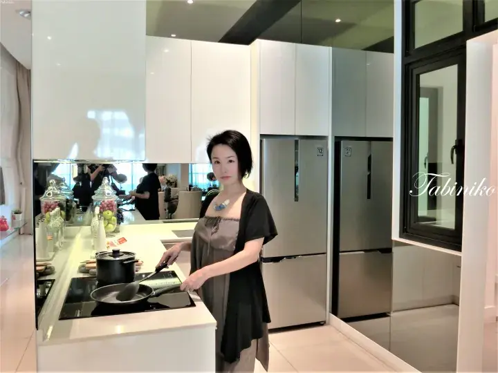 Woman cooking in a modern kitchen with white cabinets and stainless steel appliances.