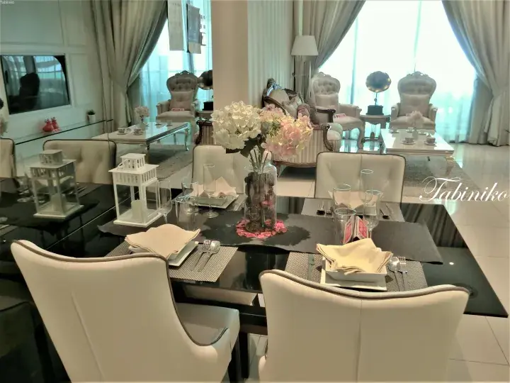 Elegant dining table with white chairs and flowers in a luxury showroom.