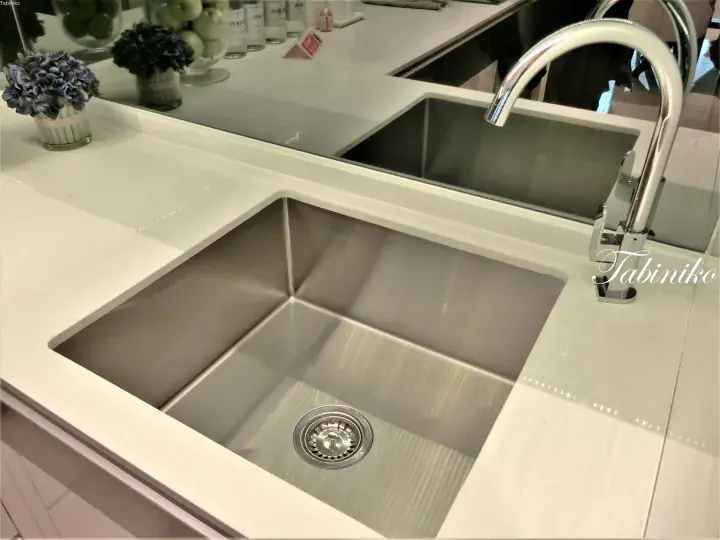 Modern kitchen sink with stainless steel basin and chrome faucet set into a white countertop.