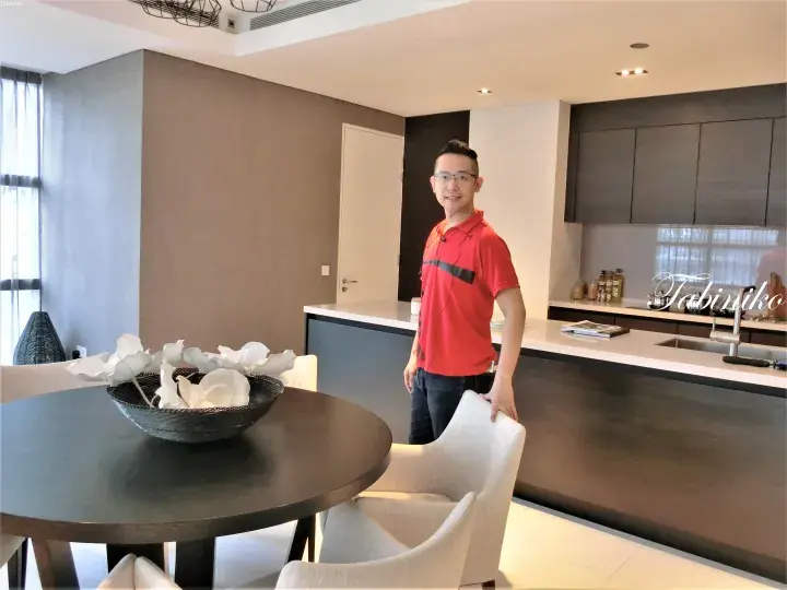 穿红衬衫的男子站在塔比尼科房产的现代厨房和餐桌前