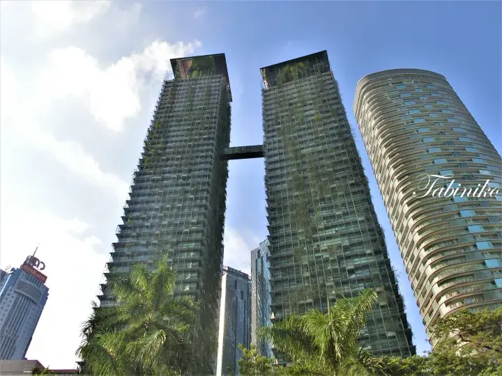 吉隆坡两座现代摩天大楼由空中连廊连接，背景可见曲线形塔楼和AmBank大厦。