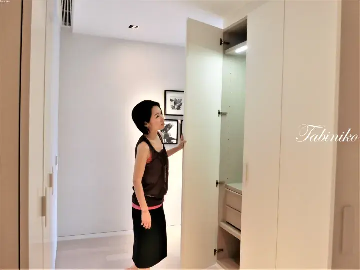 女子在明亮的极简主义房间里打开白色衣柜门。