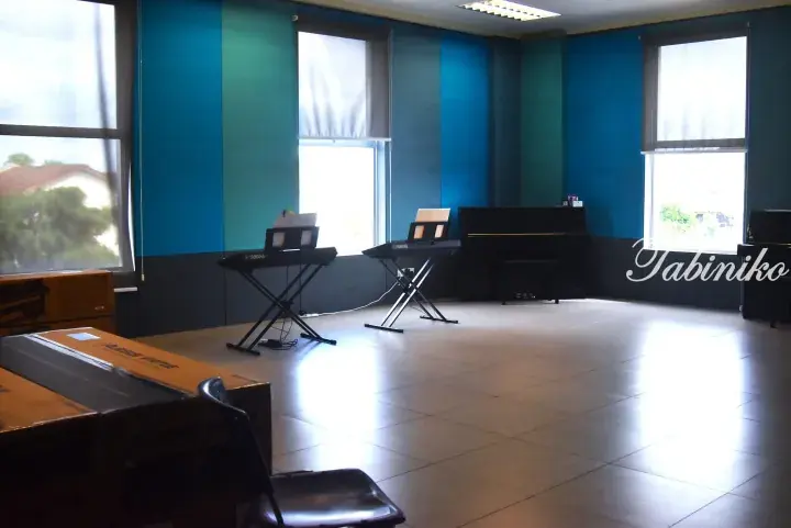 Spacious music room with blue walls, two Yamaha keyboards, and upright pianos ready for lessons.