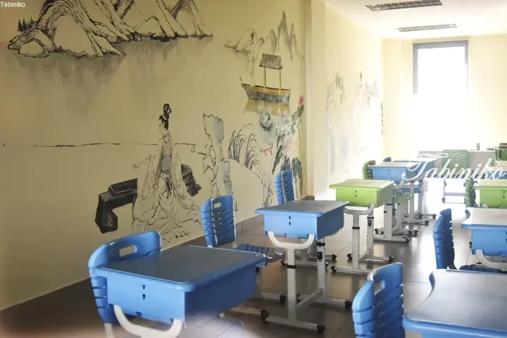 Classroom with blue desks and chairs featuring traditional Chinese ink painting murals on the walls.
