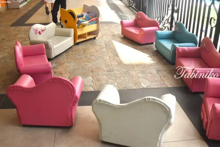 Colorful children’s sofas and a bear-shaped bookshelf arranged in a bright, tiled indoor play area.