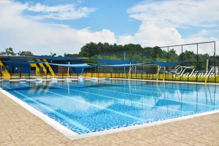 Outdoor swimming pool with blue shade sails and yellow fencing at a Malaysia property.