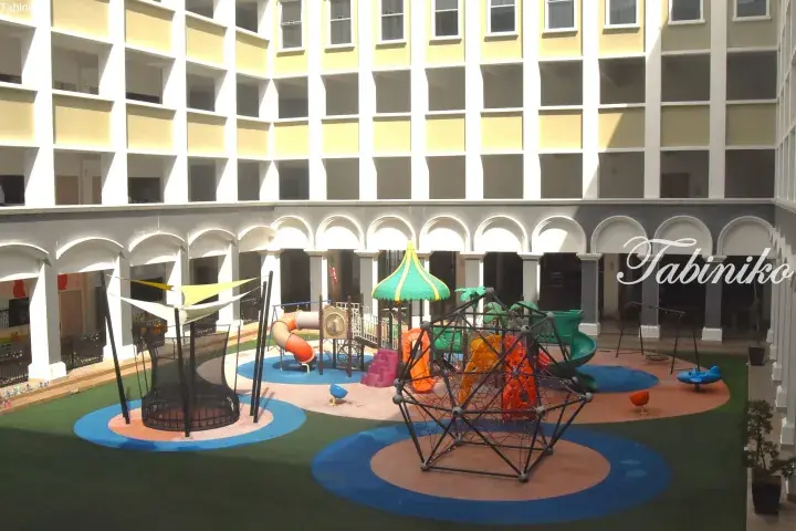 Colorful playground with climbing structures and slides in a hotel courtyard.