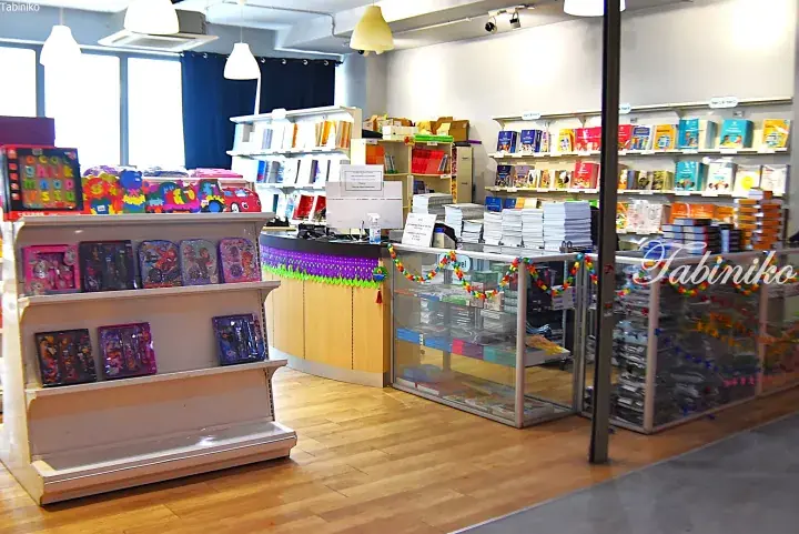 Interior of a bright school bookstore with shelves of textbooks, colorful children’s toys, and a reception counter.