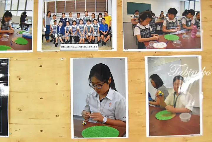 Students in uniform participate in a Primary Clay Modelling Club activity, creating green clay art pieces at classroom tables.