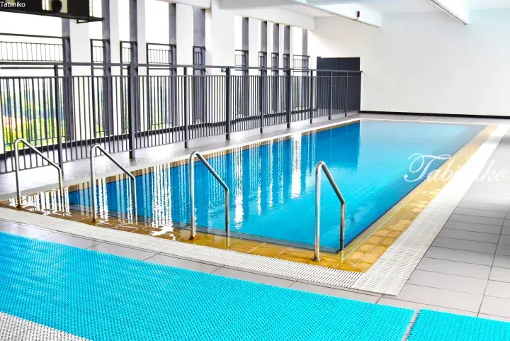 Indoor swimming pool with blue water and metal ladders at a property in Malaysia