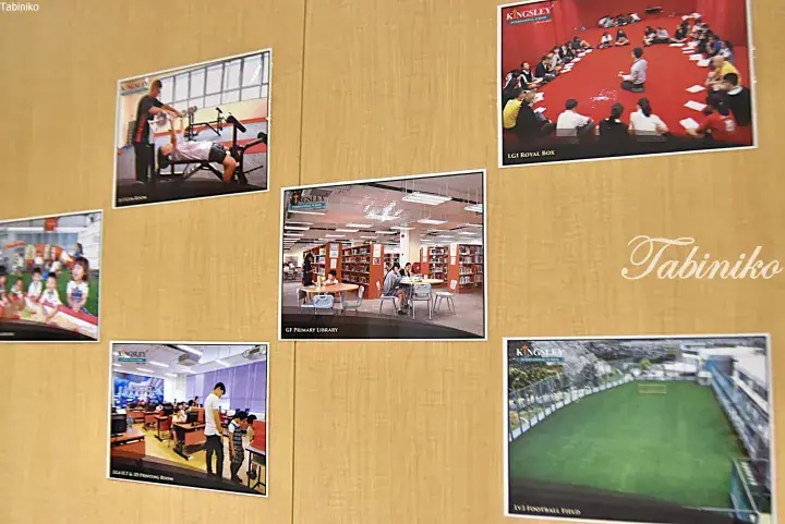 Wall display featuring photos of Kingsley International School facilities including library, gym, and sports field.