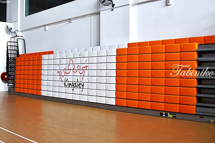 Retractable stadium seating in orange and white with a ‘Kingsley’ logo at a sports facility.