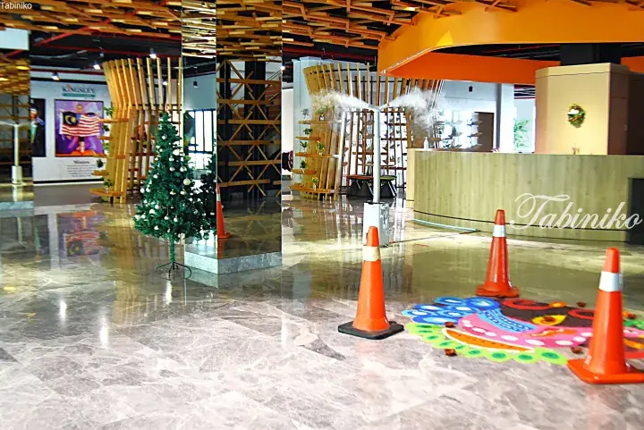 Modern lobby with marble floors, wooden accents, a Christmas tree, and misting system.